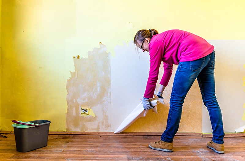 woman removing wallpaper